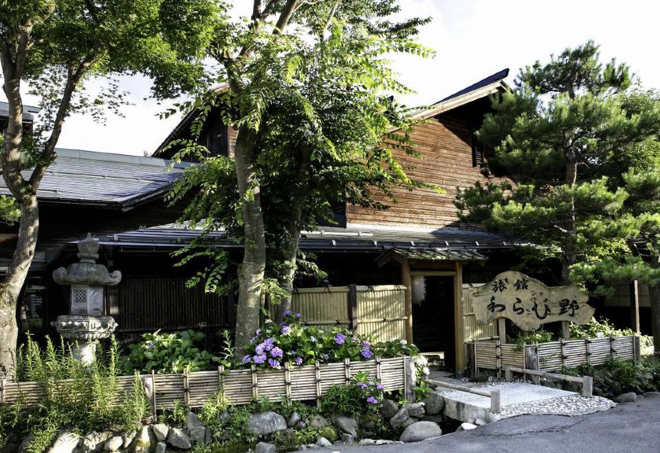 A traditional ryokan entrance is framed by mature trees.