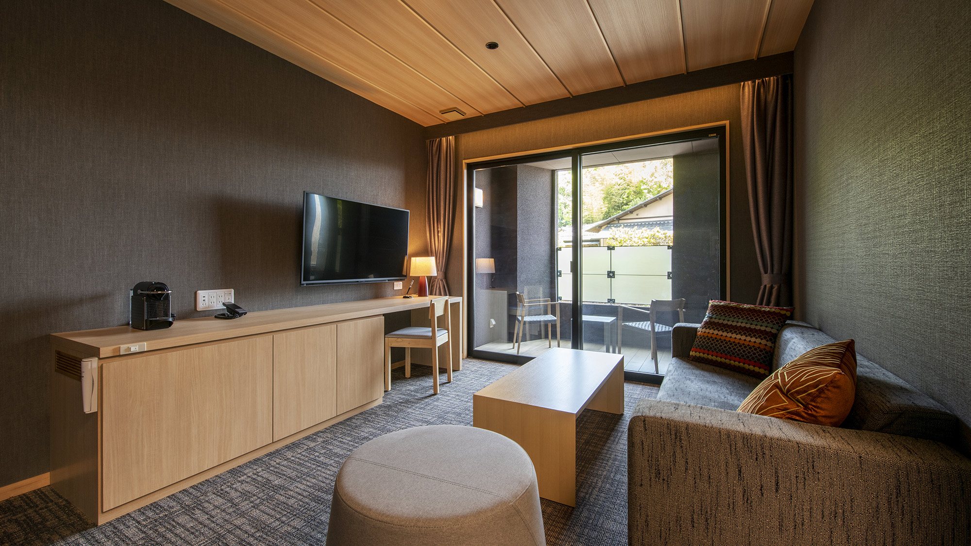 A sofa and television cabinet beside a glass terrace door.
