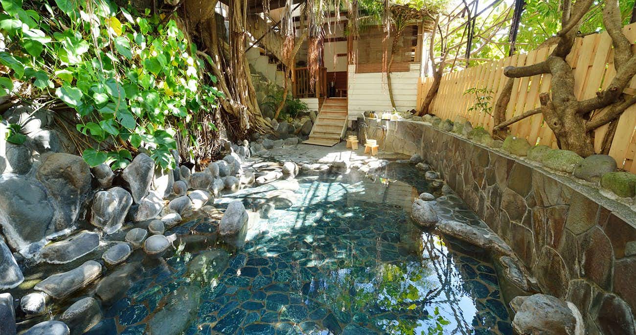 Izu Atagawa Onsen Miharuya with this scene, where a stone-edged outdoor bath reflects leafy greenery within a narrow garden enclosure.