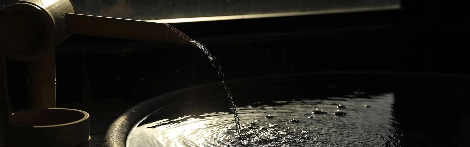 Hot spring water pours from a bamboo spout into Sakuraku's indoor onsen bath