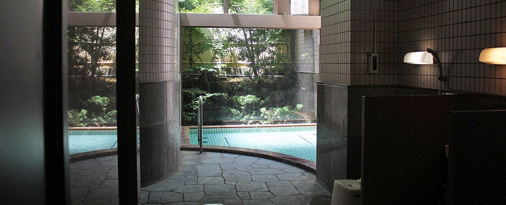 Bettei Ichika with an outdoor bath opening toward trees through glass doors.
