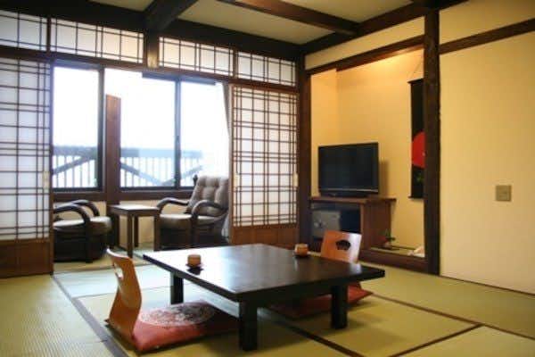 Relaxing Inn Tron Onsen Shinmei Sanso with a tatami room with low seating beside shoji windows.
