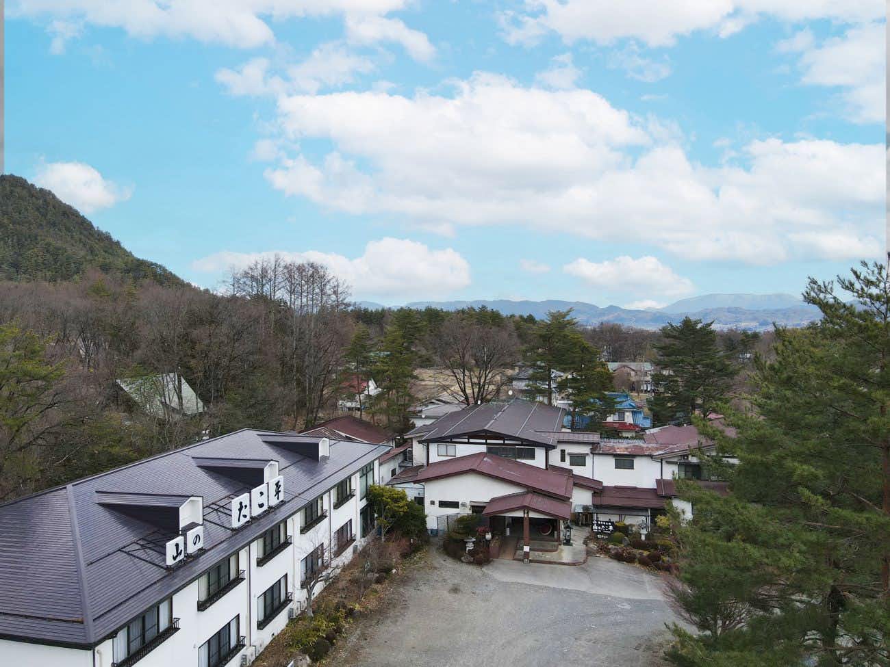 Onsen Ryokan Yama no Takohei with the white inn buildings framed by surrounding mountains.