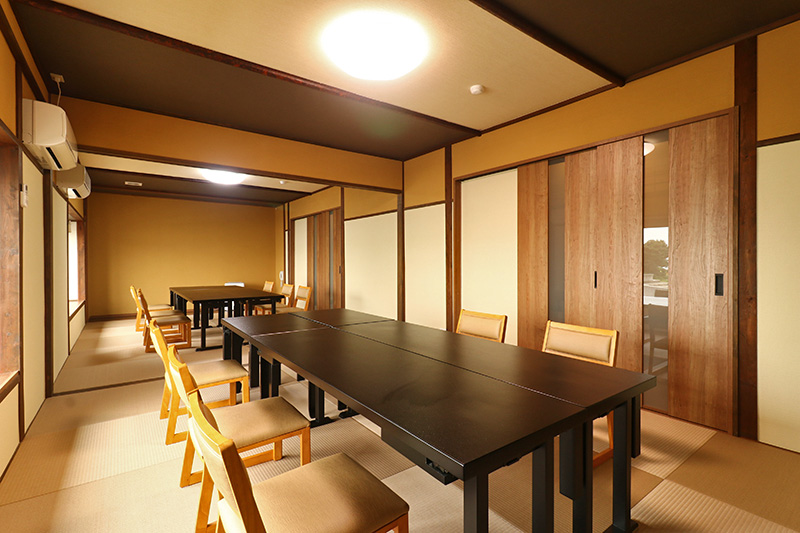 Gifuya Ryokan: A warm tatami dining room arranged with low black tables and chairs.