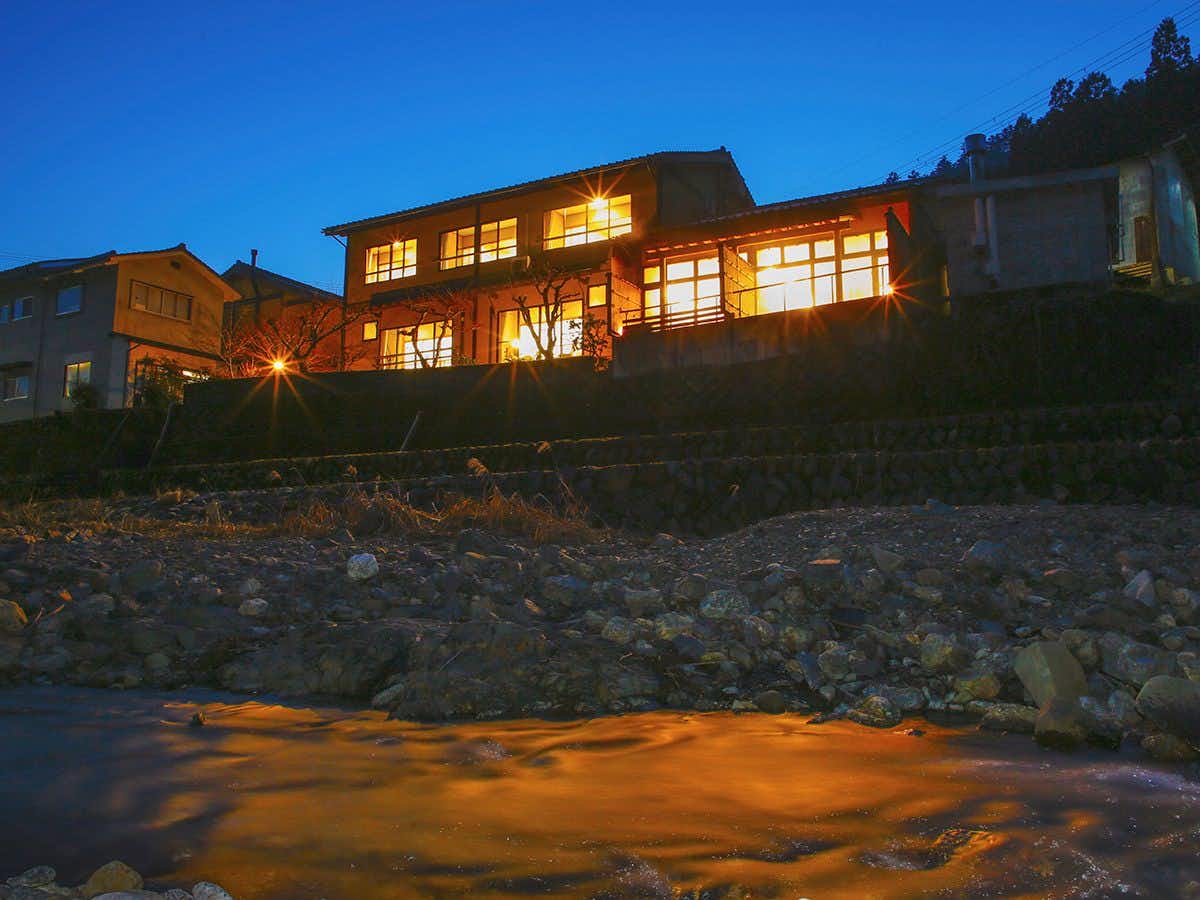Kyoto Miyama Ryokan Makuragawa with the illuminated hillside property beneath a deep blue sky.