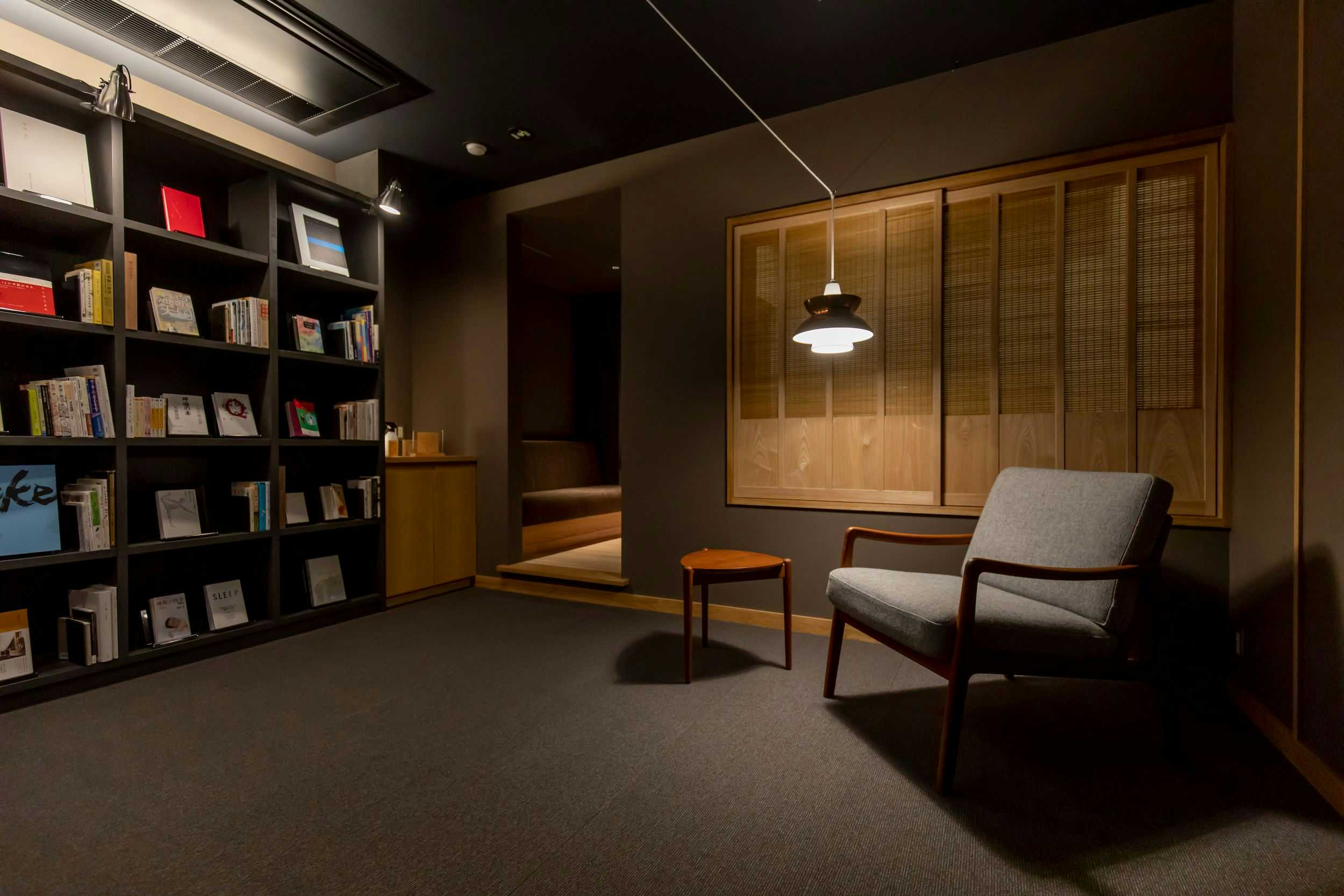 Kinosaki Onsen Sensui Interior lounge with floor-to-ceiling bookshelves, modern chairs, and warm wood tones.