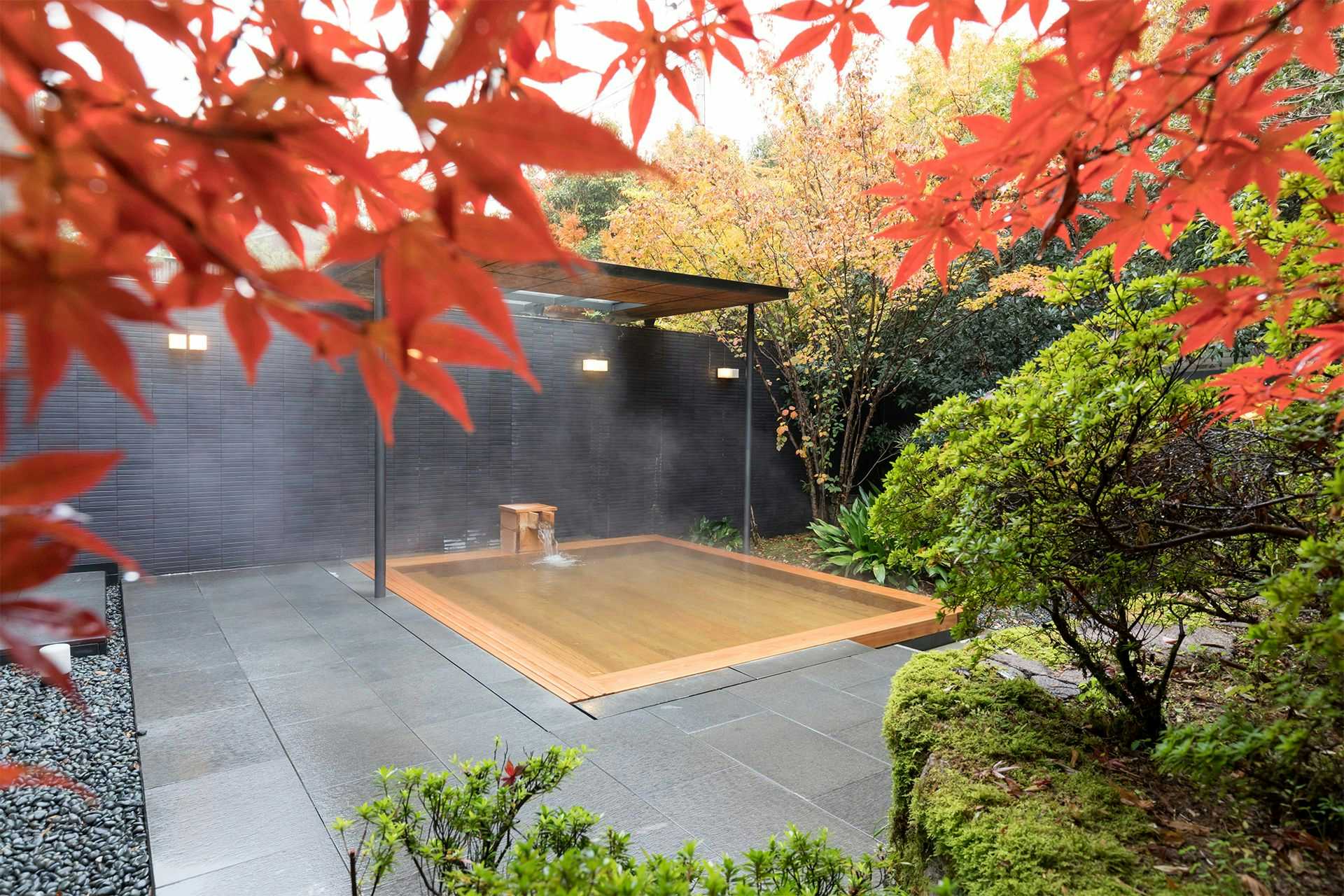 Wataya Besso with an outdoor timber bath framed by vivid red maple leaves.