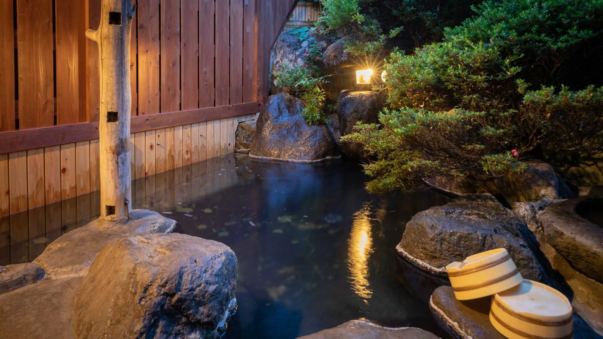 Ryokan Gizan with an open-air rock bath glowing in the evening garden.