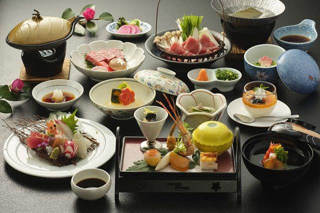Kirishima Hotel Multiple plated dishes including sliced seafood, cooked items in dark bowls, garnishes, and serving vessels arranged on table.