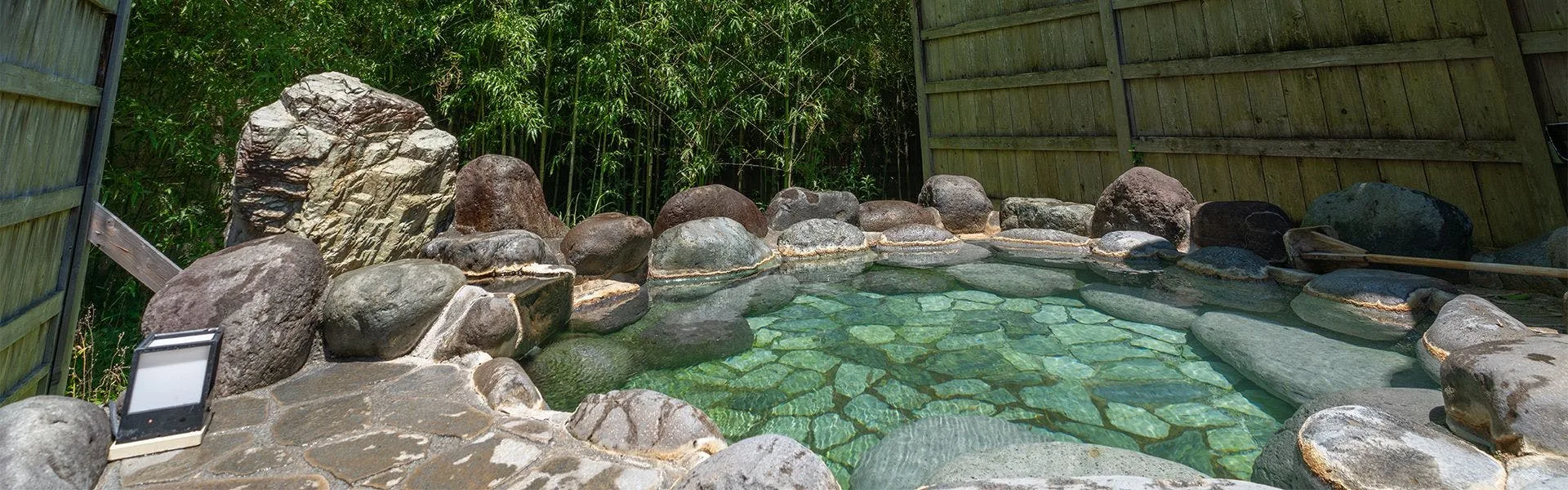 Rock-rimmed rotenburo outdoor bath enclosed by bamboo grove in Oku-Atagawa