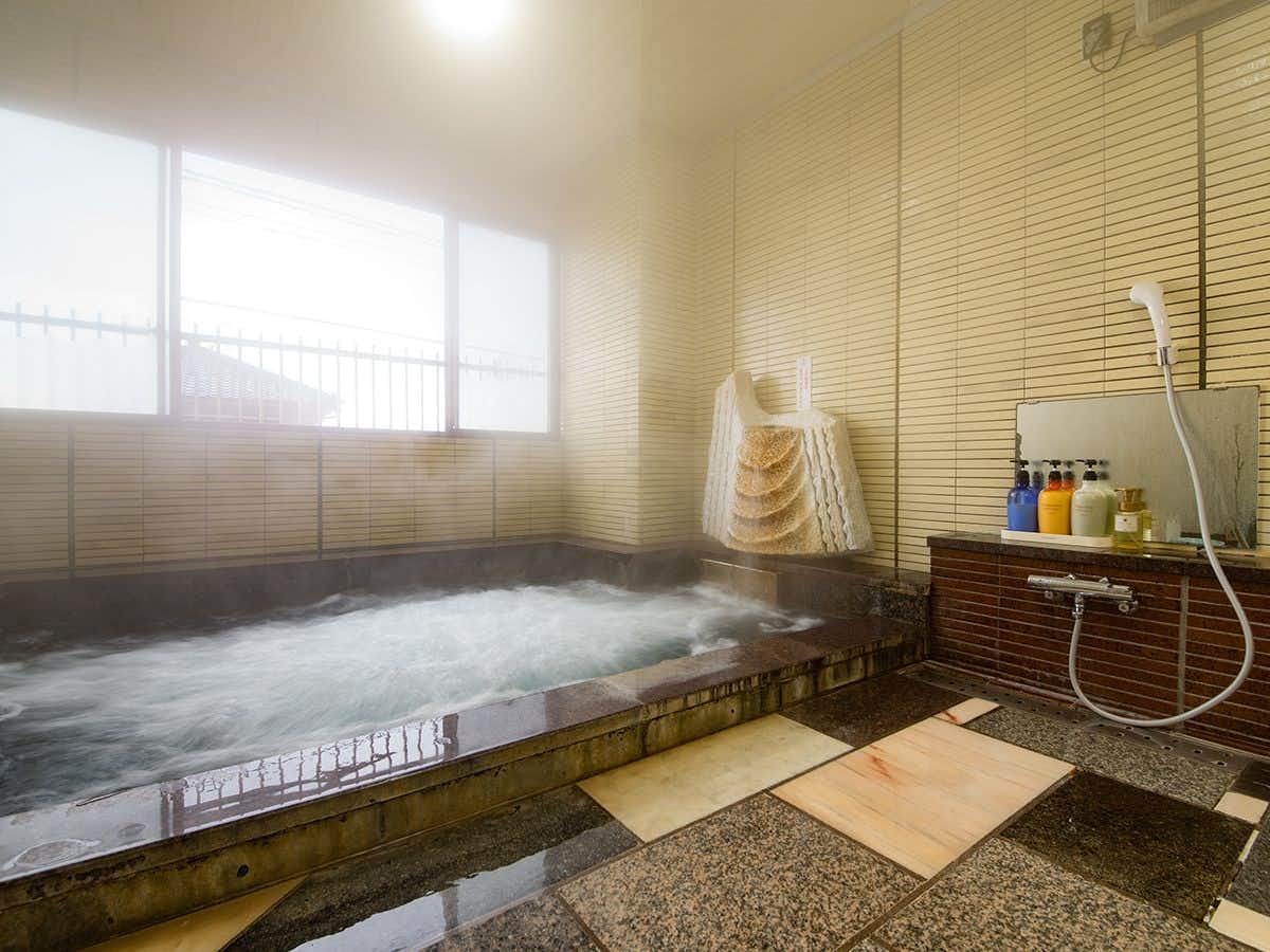Kuriya Onsen Imai Ryokan with this scene, where steam rises from a long indoor bath lined with pale stone and large windows.