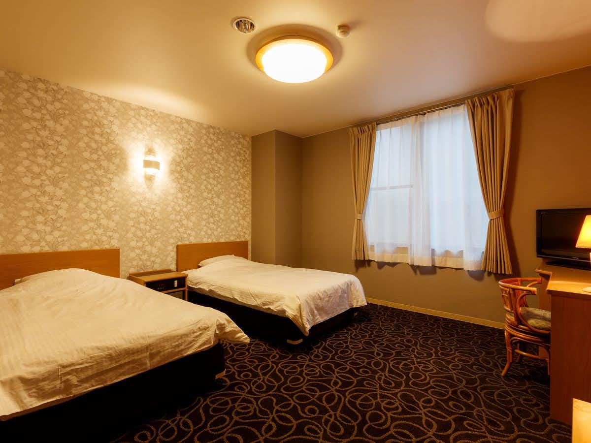 Tokura Kamiyamada Onsen Umemura Ryokan Uguisutei with a modern twin bedroom with patterned carpet and cream curtains.