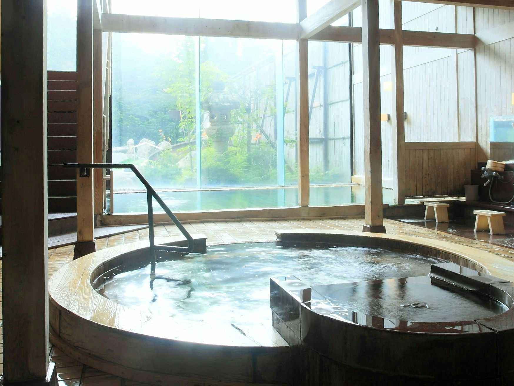 Okada Ryokan Warakutei with a bright indoor bath, timber railings, and garden-facing windows.