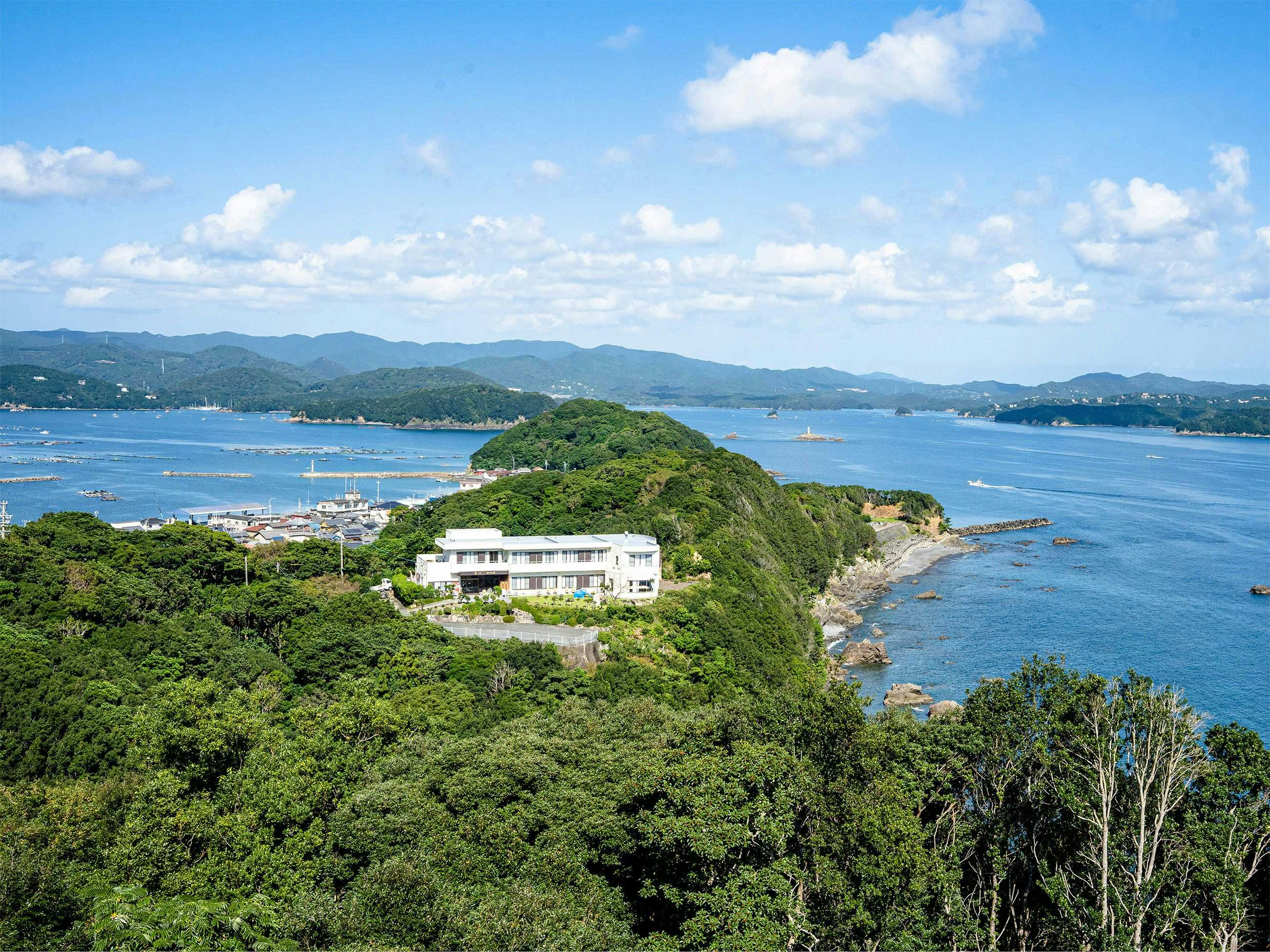 New Hamaguchiya Ryokan with an elevated view of the ryokan among green coastal hills.