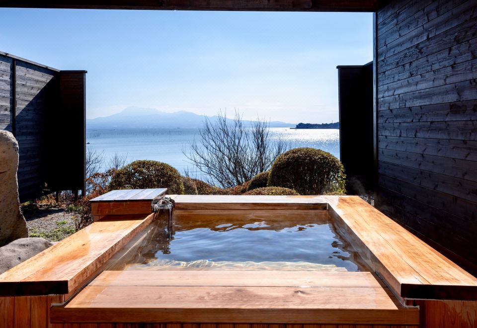 A private-looking bath opens toward a broad coastal view.