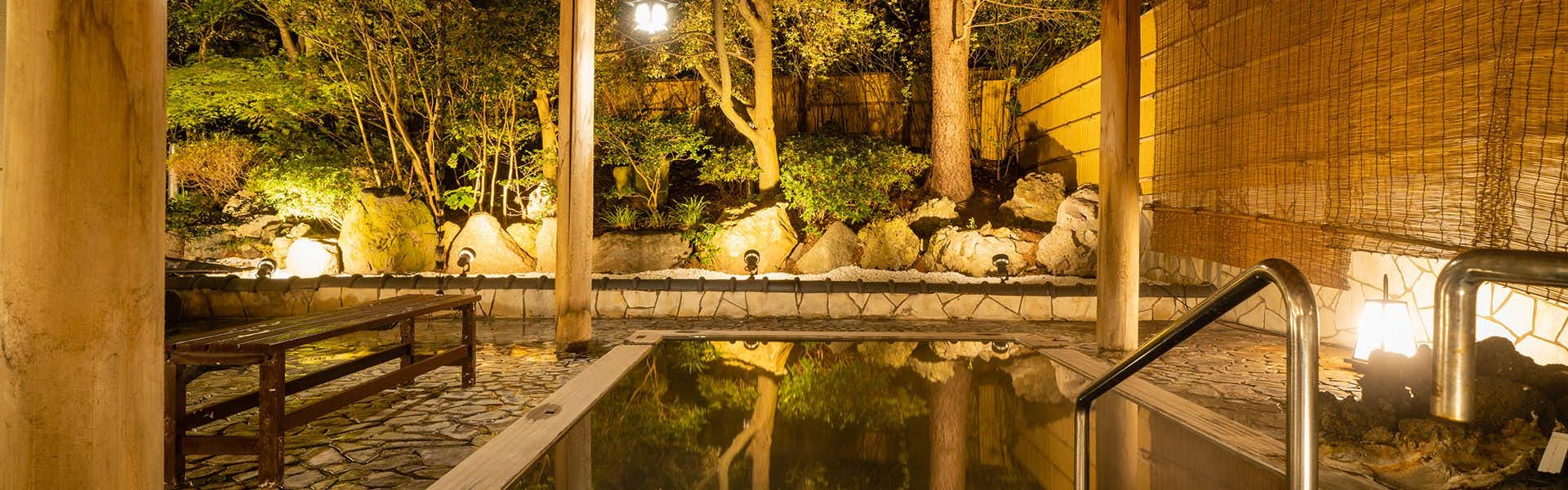 Accommodation Overlooking the Echigo Plain and Yahiko Mountain Range - Hoho - with an outdoor bath glowing among dark forest trees.