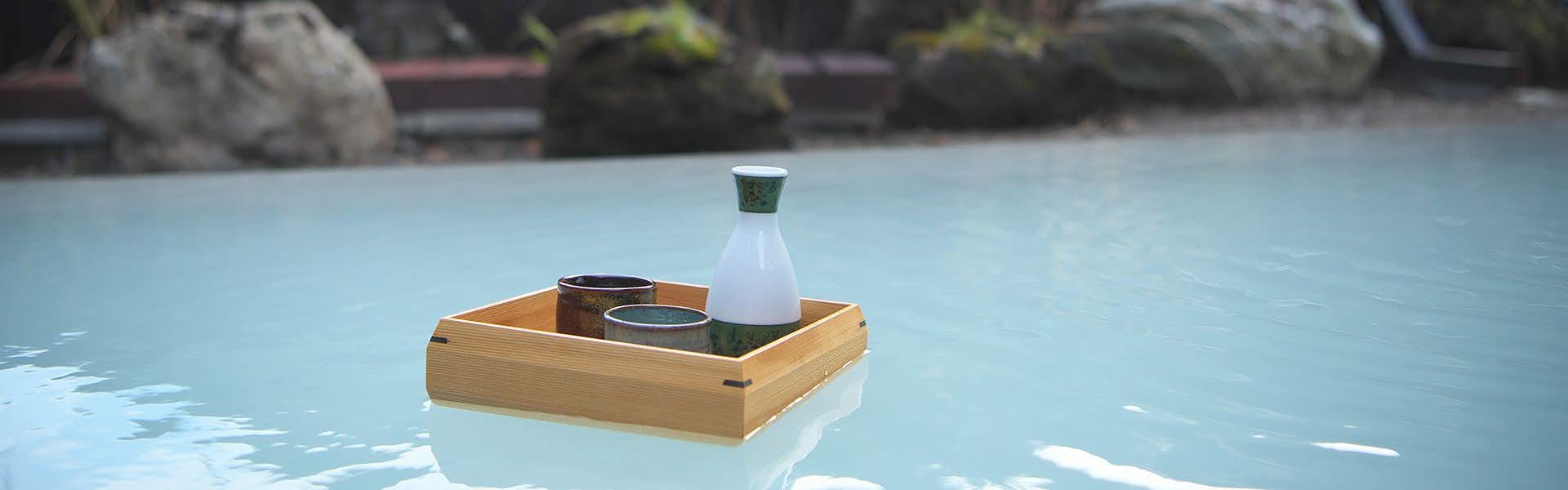Shirakami Yatate Yugen Village Inn Hikage Onsen with a milky outdoor bath with a floating sake tray.