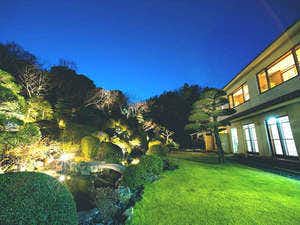 Shogen Mountain Villa with guest buildings glowing beyond a landscaped garden at dusk.