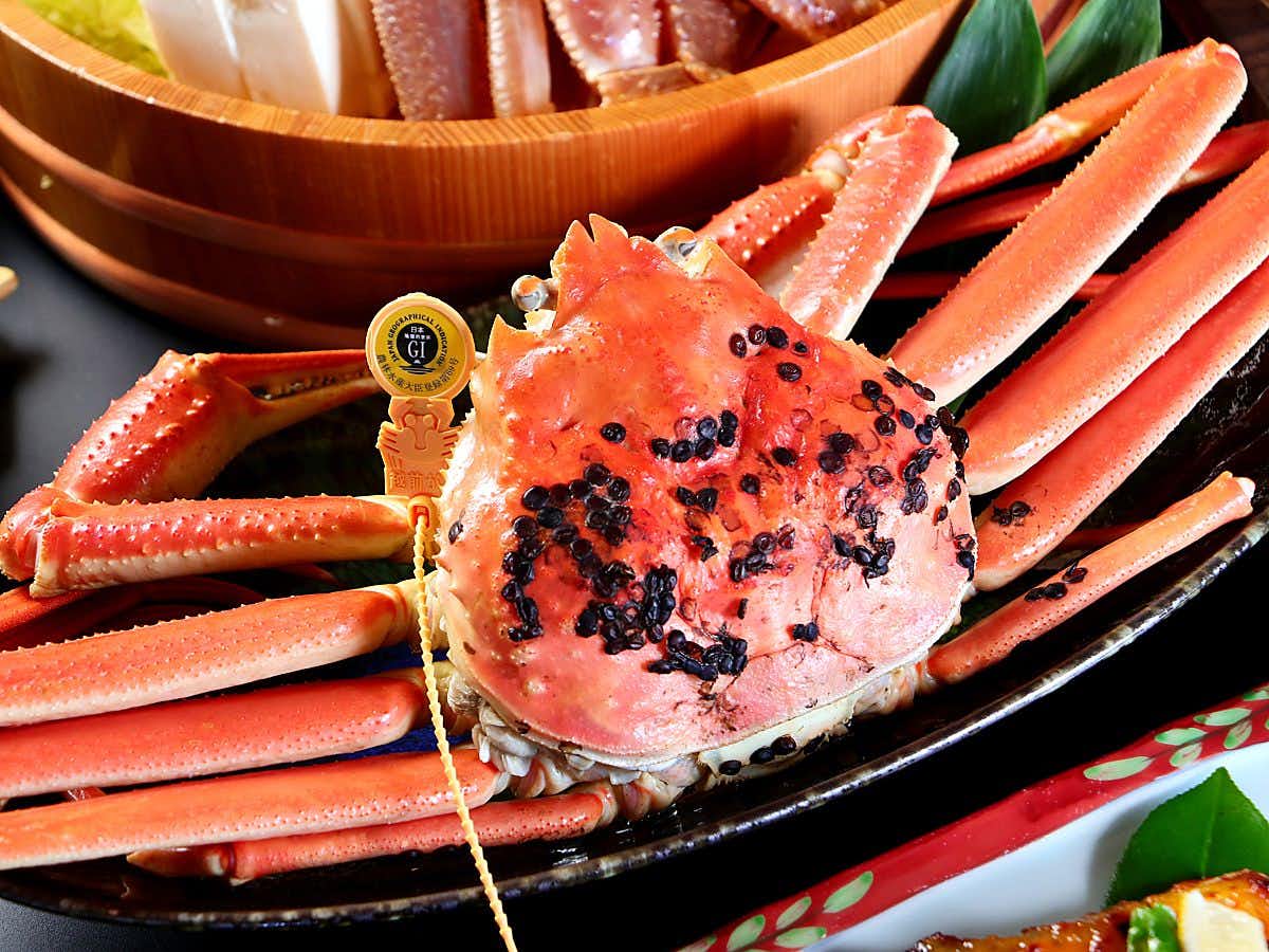 Natural Onsen Okasanya Irokasane with a whole crab presented on a black dinner plate.