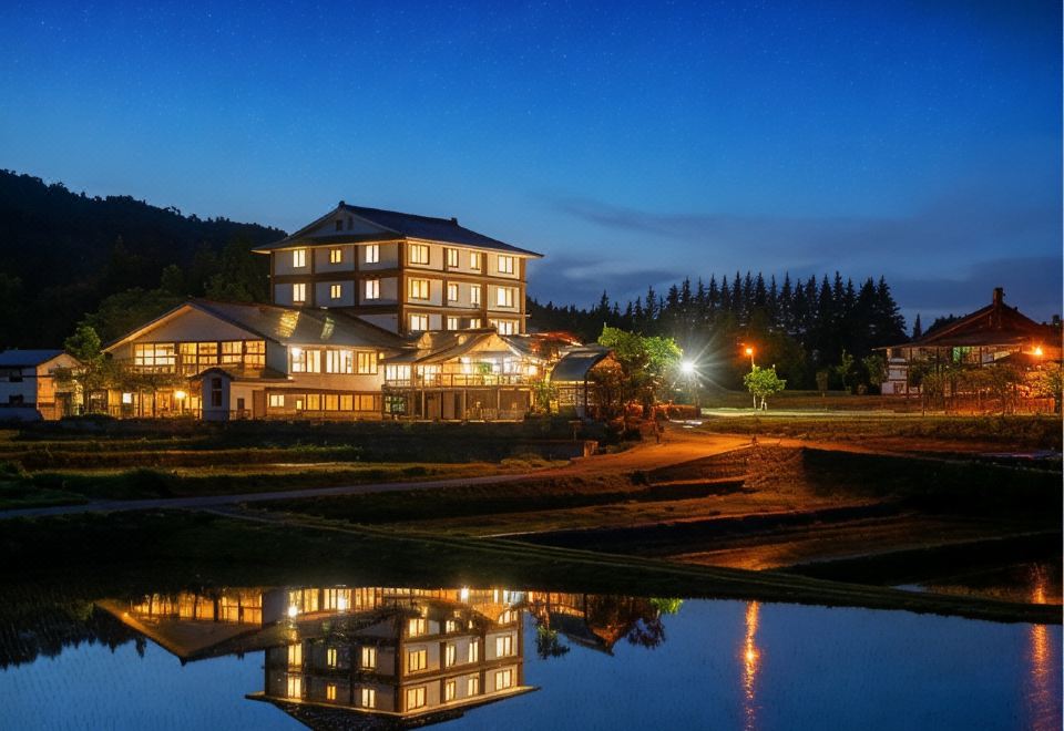 A lit hotel reflected in a pond at night.