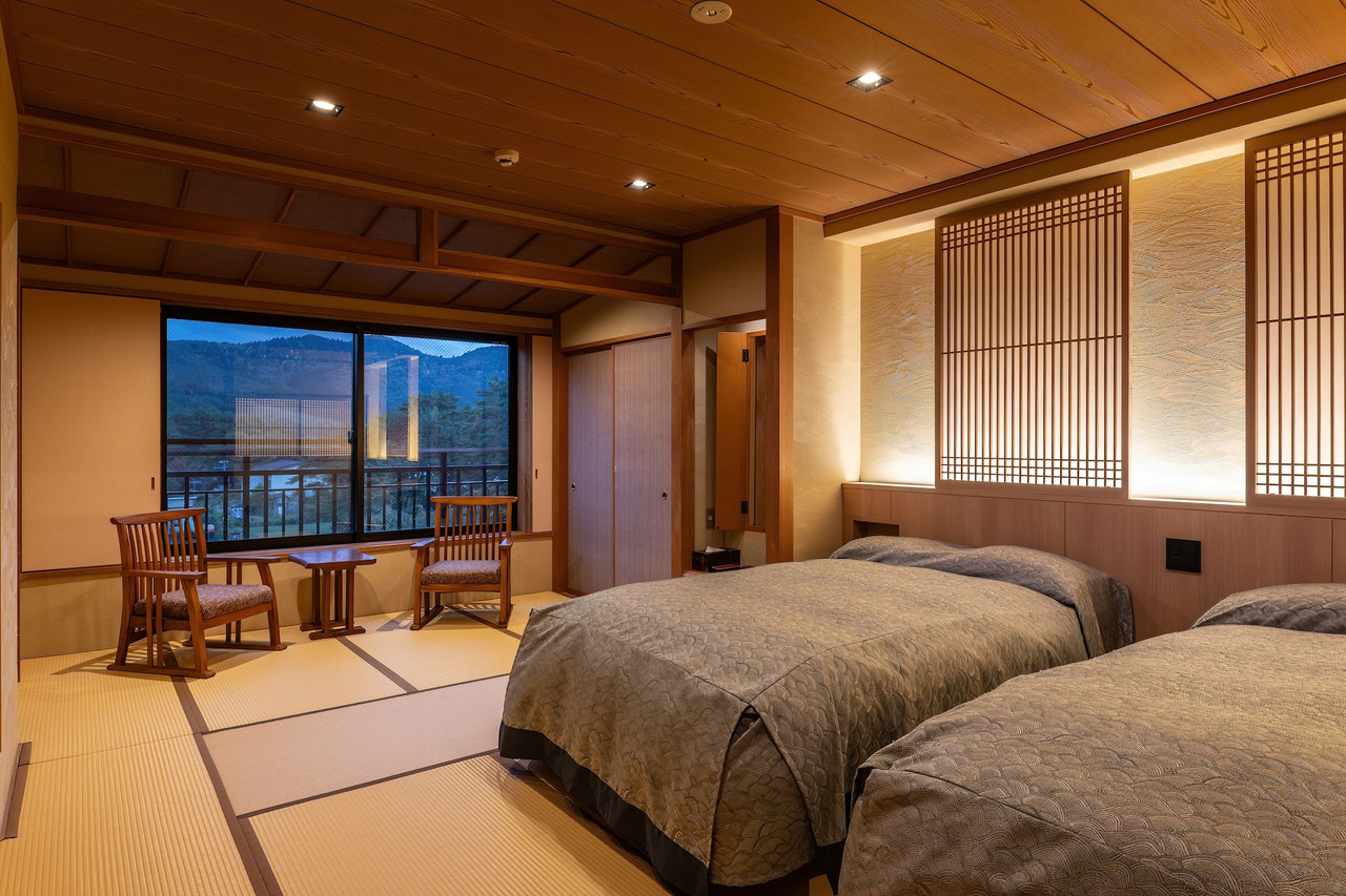 A warm room combines beds, tatami, and a mountain view.