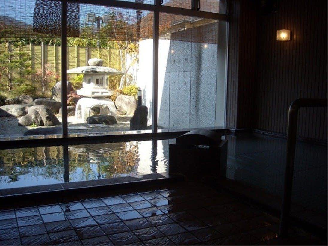 Annex Fujiya Ryokan with a dark stone bath facing a lantern and garden pond.