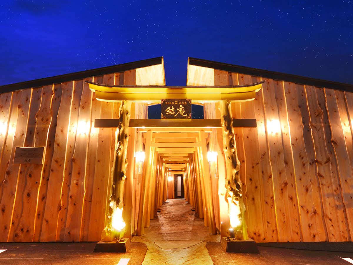 Japanese Inn Utsuwa Beppu Kannawa with an illuminated timber corridor beneath a deep blue night sky.