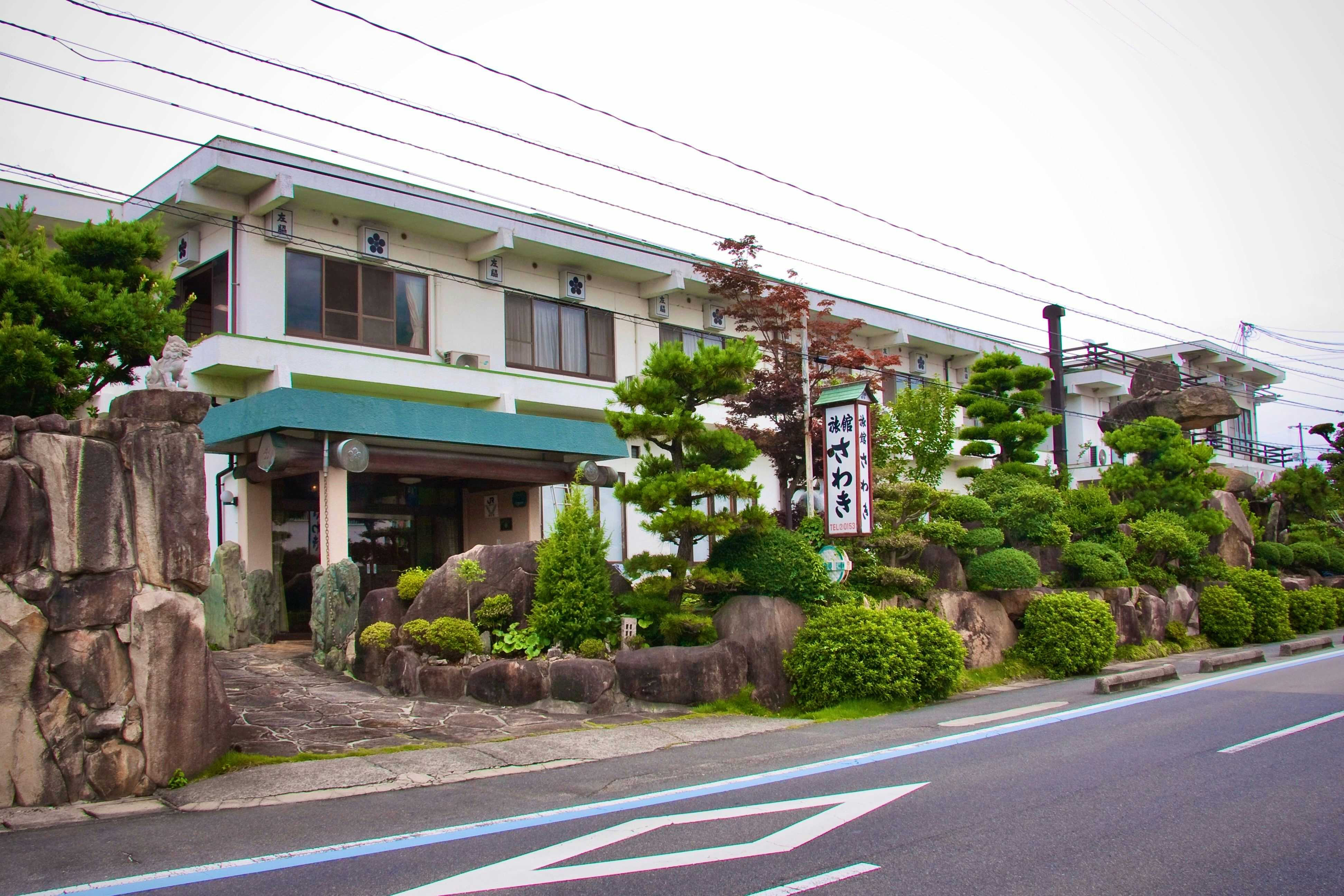 Ryokan Sawaki with the streetside facade bordered by carefully shaped pine trees.
