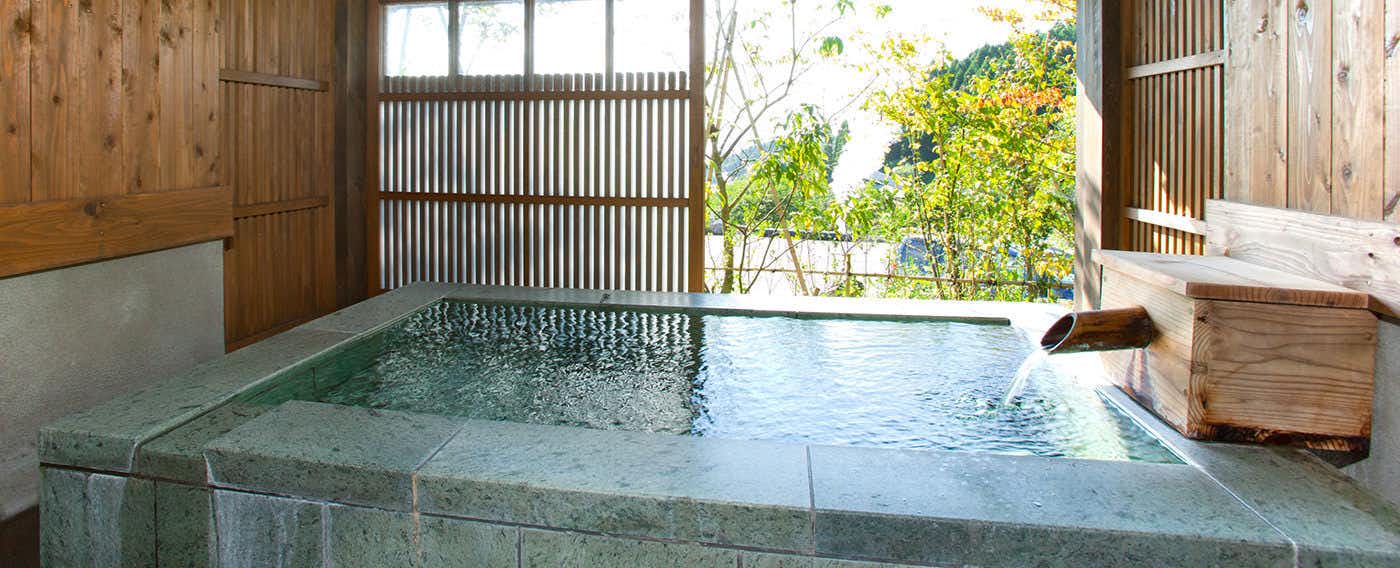 Ryokan Sansui with a private rectangular bath beside timber walls and garden windows.