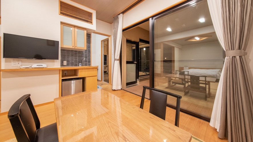 A wooden dining table beside a balcony door and television.