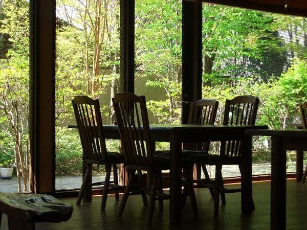 Yufuin Onsen Ryokan Hananomai with a quiet dining room with dark chairs and forest windows.