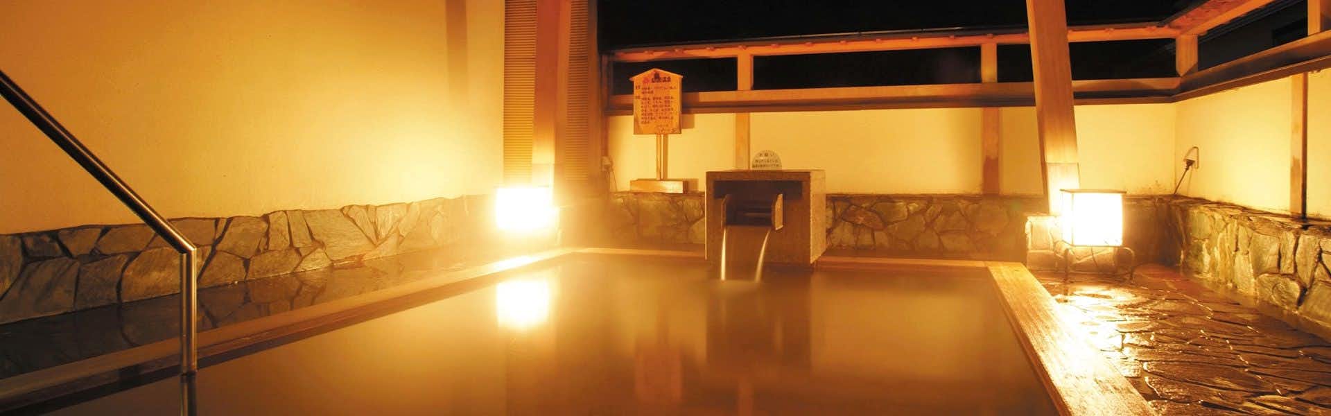 Yahiko Onsen Shiki no Yado Minoya with an indoor mineral bath beneath warm timber beams.
