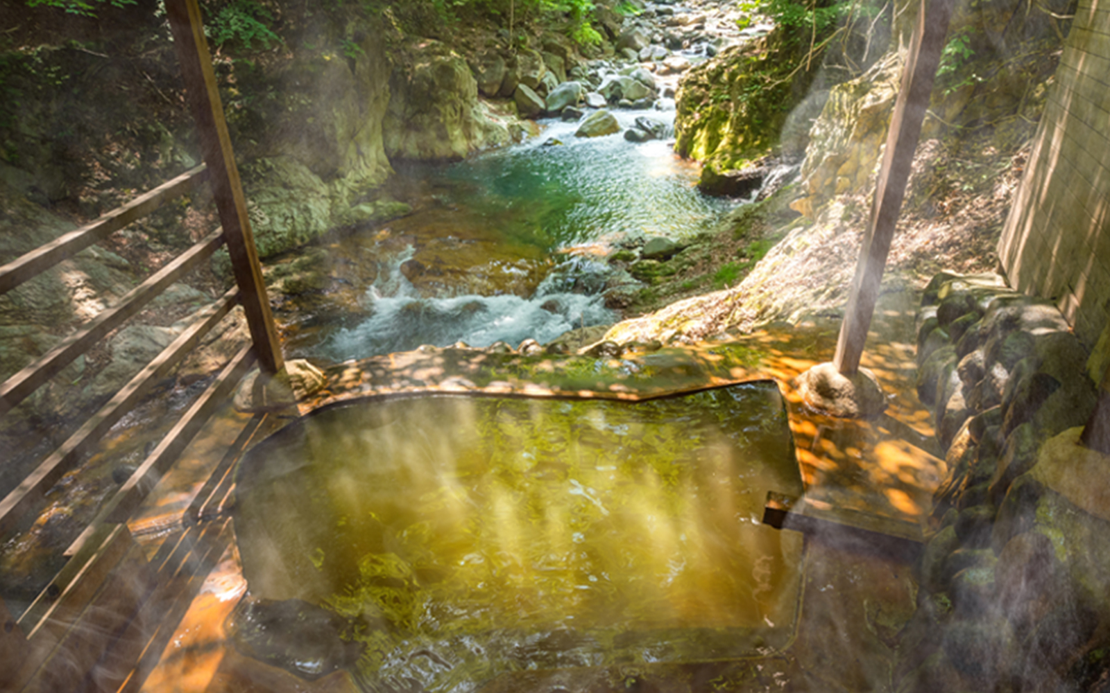 A sheltered bathing pool overlooks a clear stream flowing through a wooded ravine.