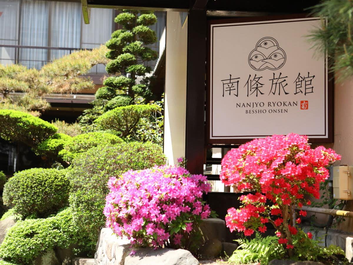 The property sign surrounded by neatly clipped flowering shrubs.