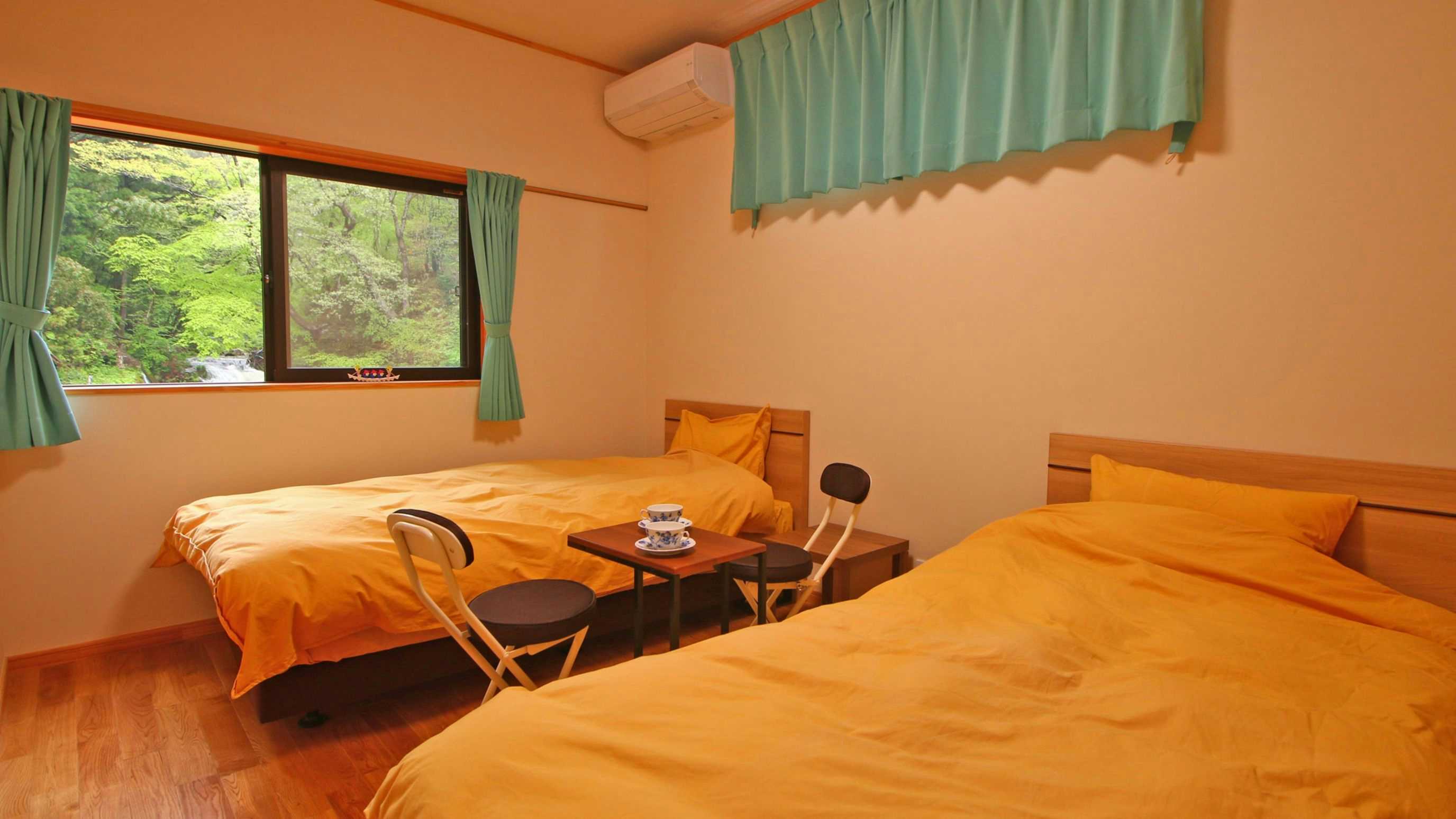 Takinoyu Ryokan with a simple twin bedroom with orange bedding and garden window.