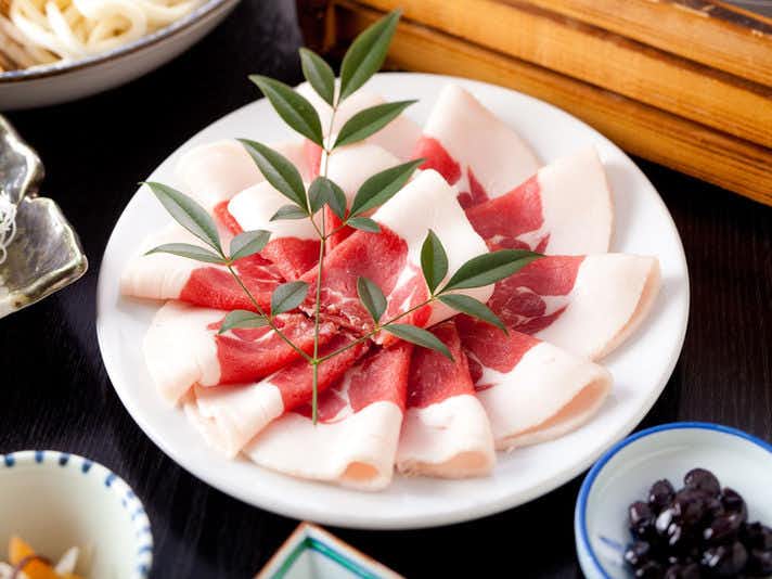 Ryokan Kuboji with thick fish slices arranged with green leaves on a white plate.