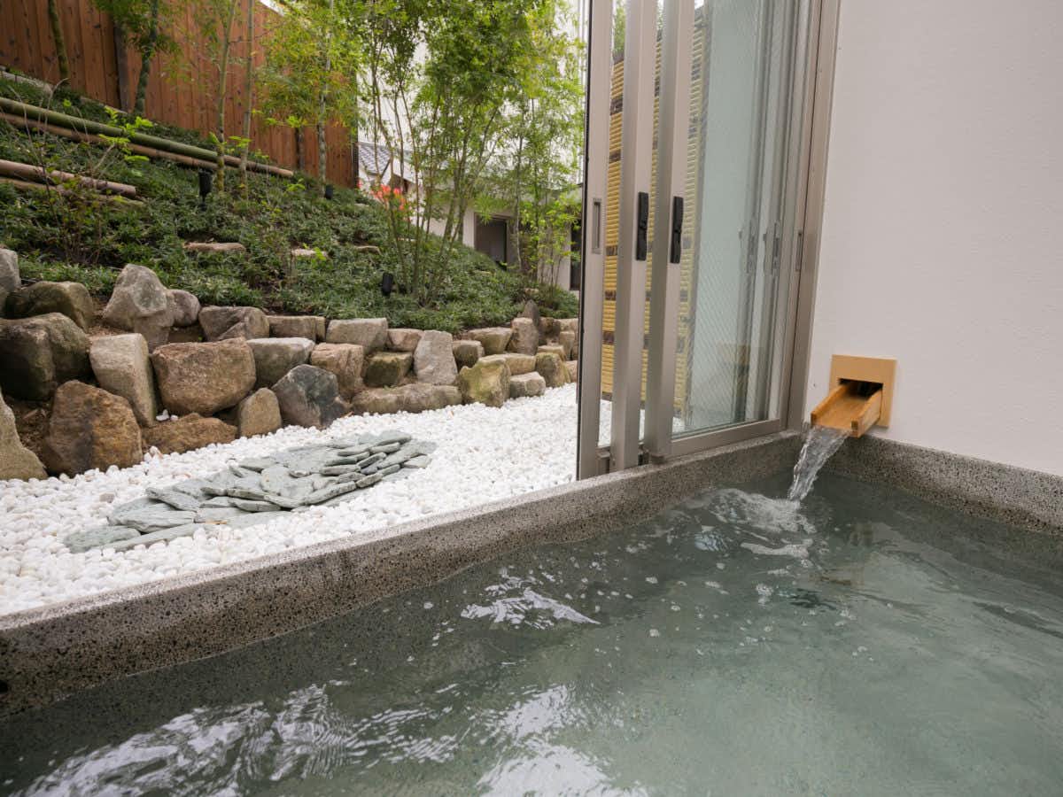 Yunogo Onsen Yasashisa no Yado Chikutei with a private stone bath beside white gravel and bamboo.