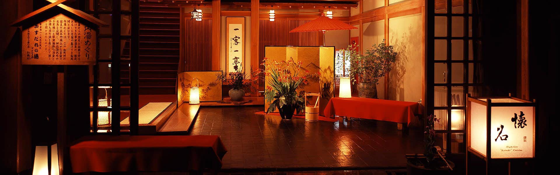 Kusatsu Onsen Tenojiya lantern-lit wooden lobby with low tables and a red parasol