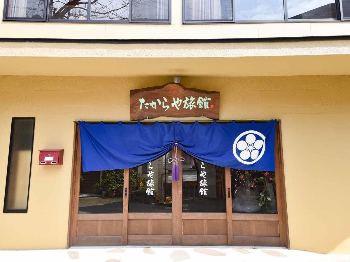 The blue-curtained timber entrance beneath the property sign.