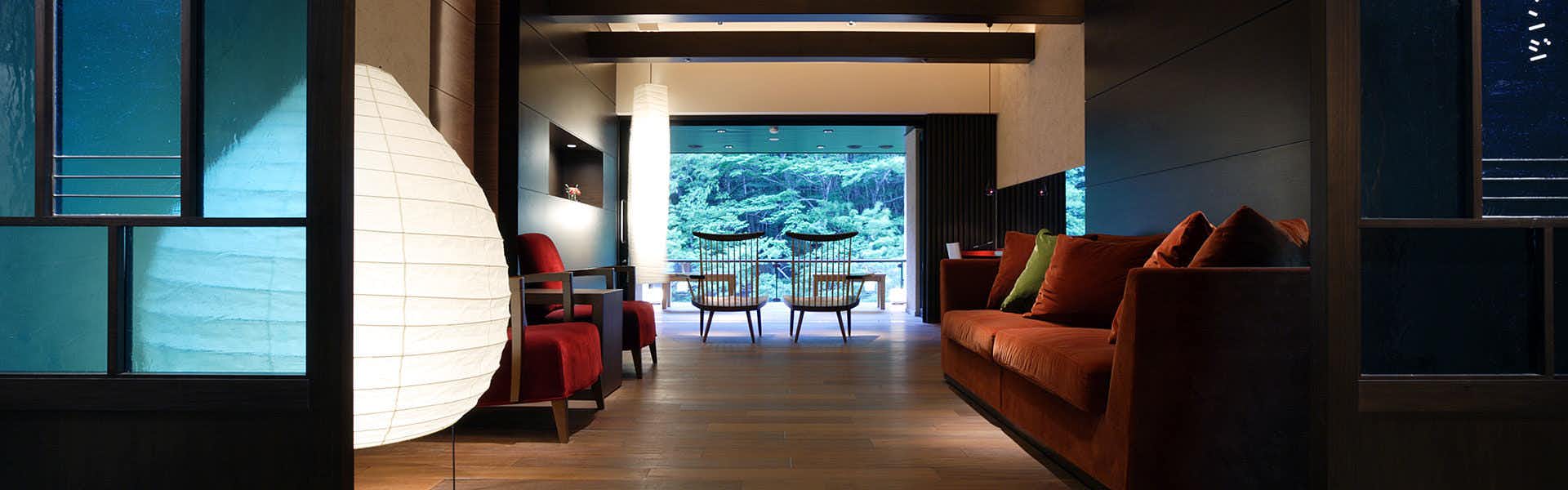 Shima Onsen Yamaguchikan with red chairs, a tall paper lamp, and a windowed sitting area