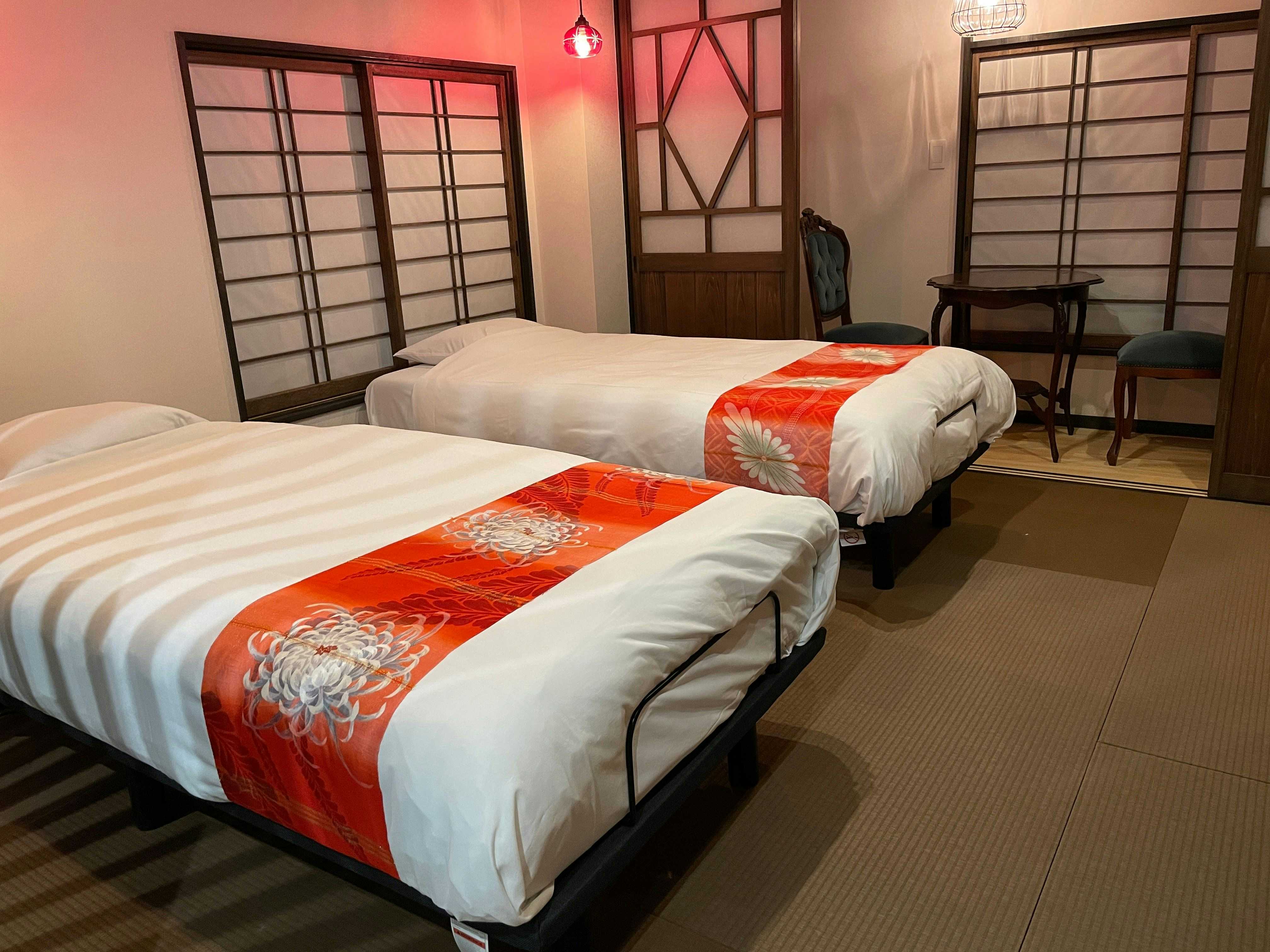 Aromatic Flower Hospitality - Susaki Ryokan with a twin bedroom accented by red patterned runners.