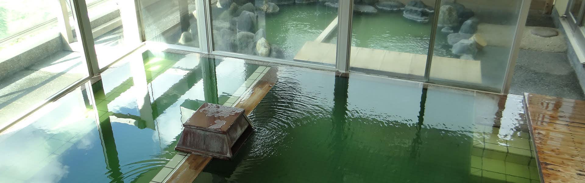 Sakihana Onsen Bokukaku with a green-tiled indoor bath beside broad windows.