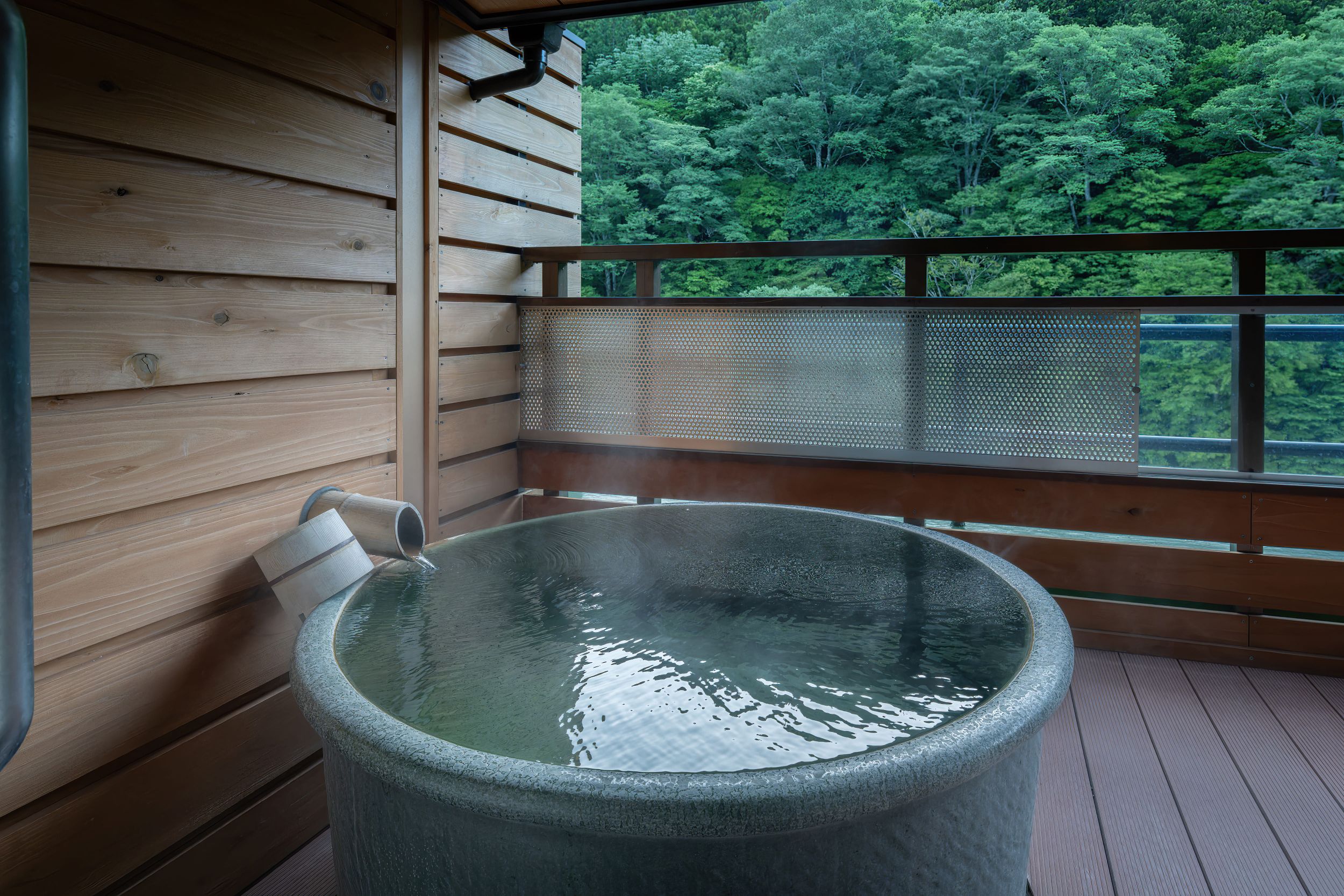 A round private bath facing forested river slopes.