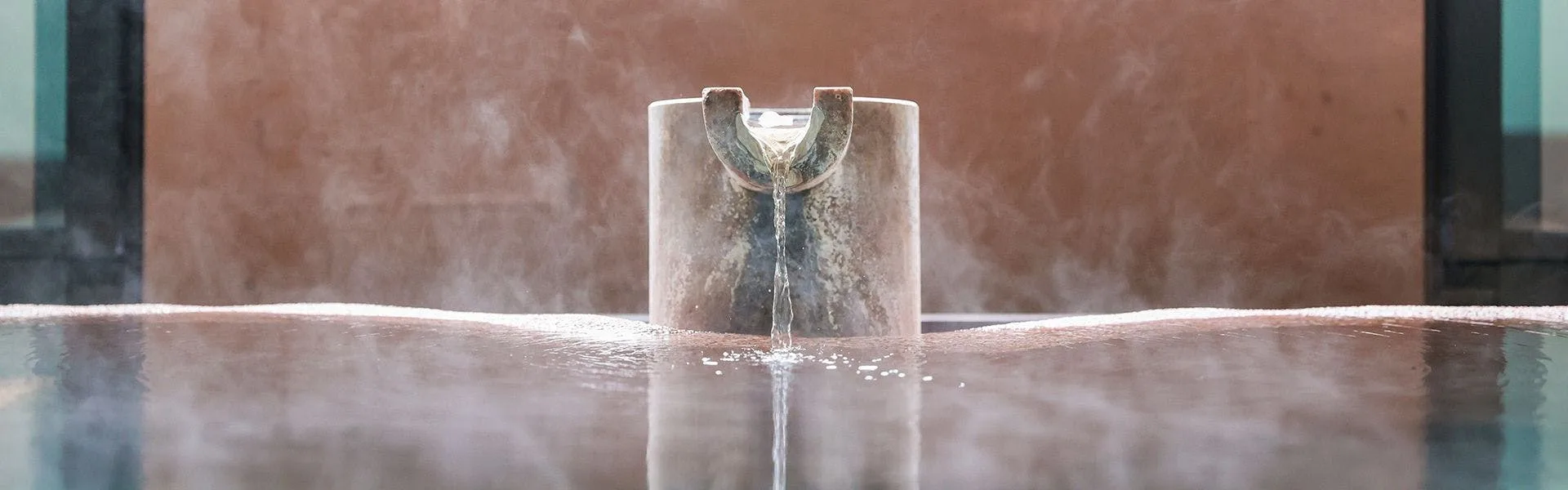 Hot spring water pouring from a stone spout into an Izu onsen bath