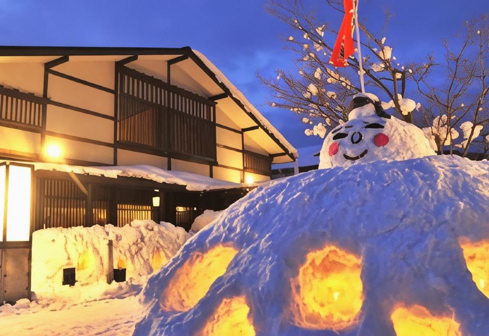A snow sculpture stands outside the ryokan beneath winter lights.