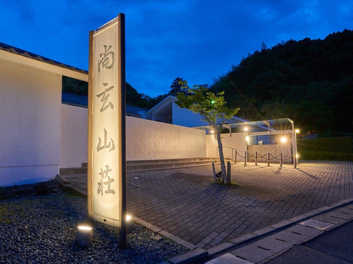 Shogen Mountain Villa with the illuminated approach rising toward dark mountain forest.