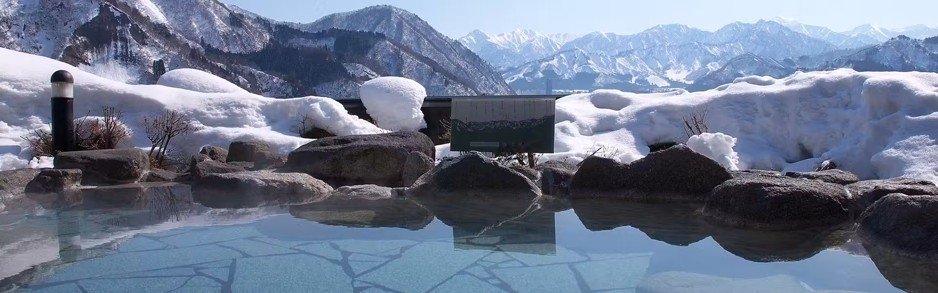 Onyuyado Nakaya with this scene, where a rock-edged open-air bath faces snow-covered mountains.