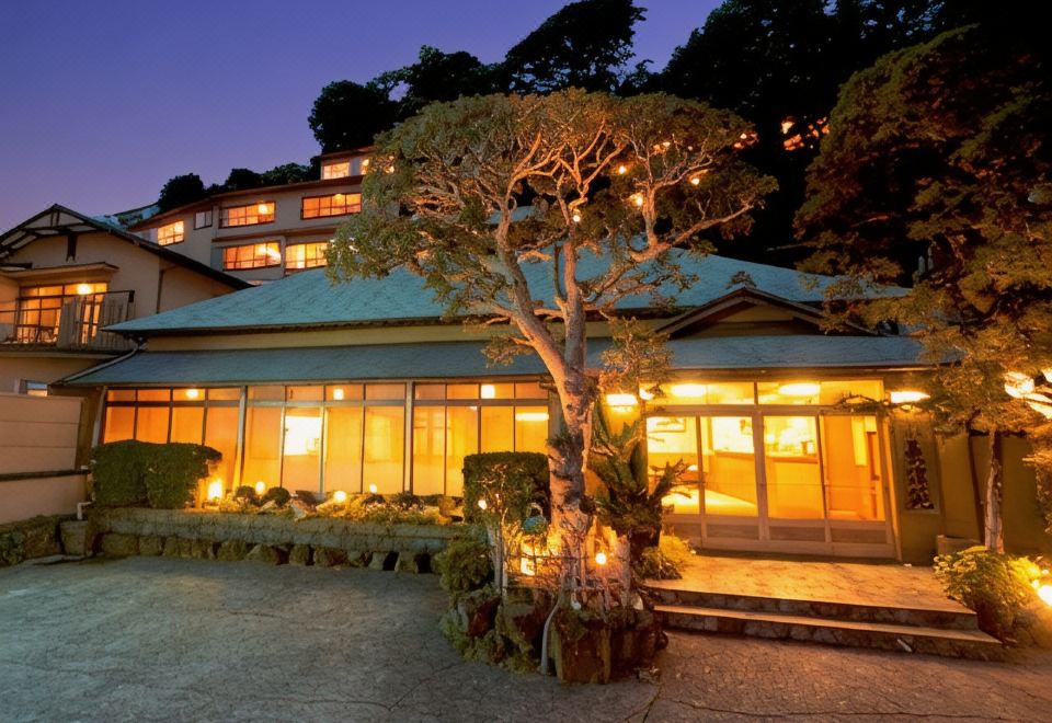 A traditional inn glows among trees at night.