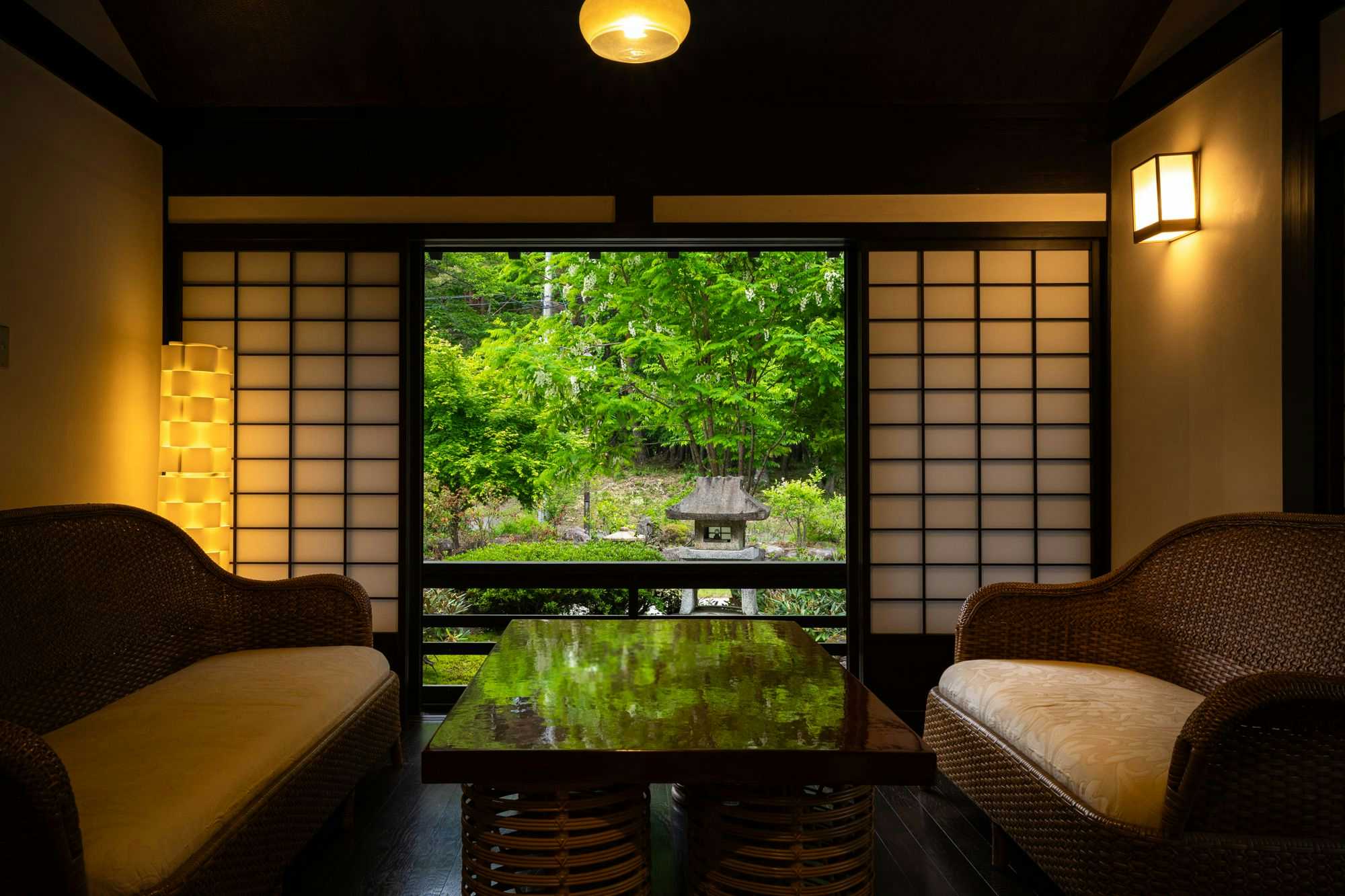Omachi Onsenkyo Ryoan Kawaki with curved seating beside a window overlooking bright greenery.