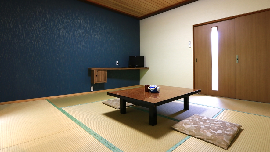 A tatami guest room with a blue accent wall and low table.
